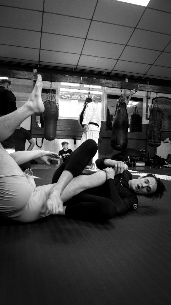 Matt Ludlow, head coach: a black and white mat shot of two grapplers with heavy bags behind them